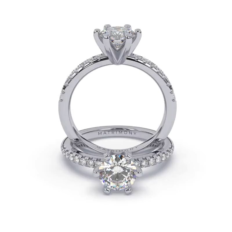 Hermoso anillo de compromiso con piedras laterales y diamante redondo. Este modelo se encuentra disponible con piedras de zirconia o diamante, además de poderse crear con oro de 9k, 14k, 18k y platino.