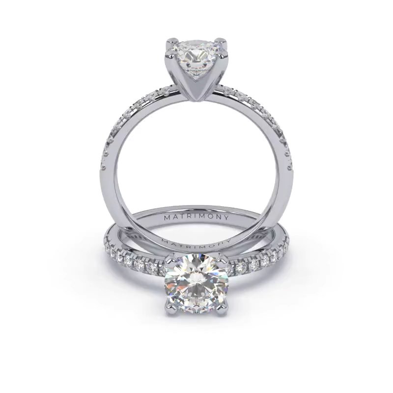 Hermoso anillo de compromiso con piedras laterales y diamante redondo. Este modelo se encuentra disponible con piedras de zirconia o diamante, además de poderse crear con oro de 9k, 14k, 18k y platino.